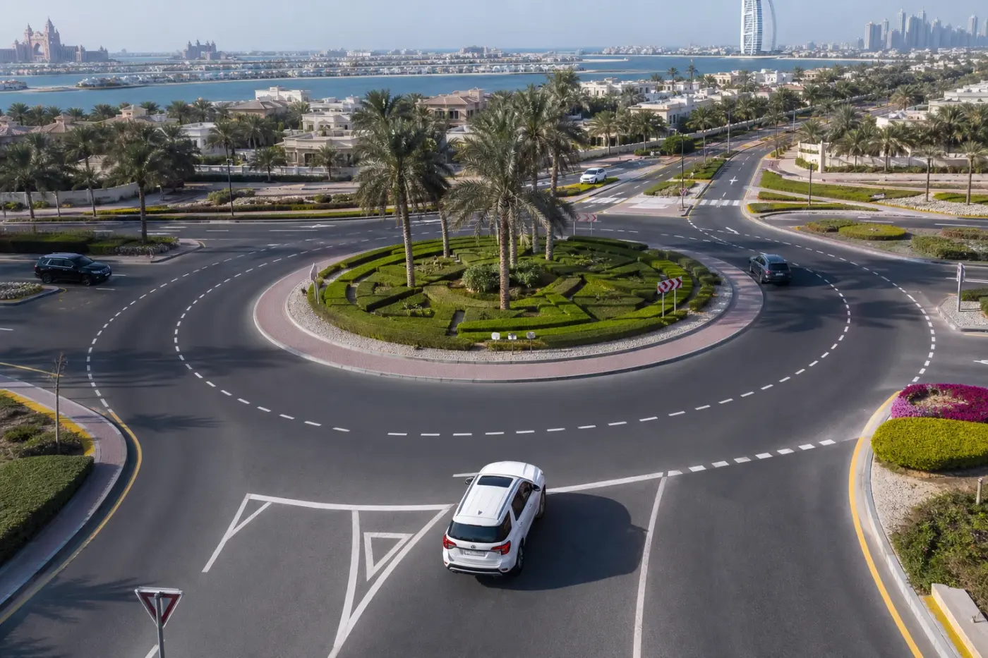 Dubai roundabout approach with clear lane markings and rental car entering safely
